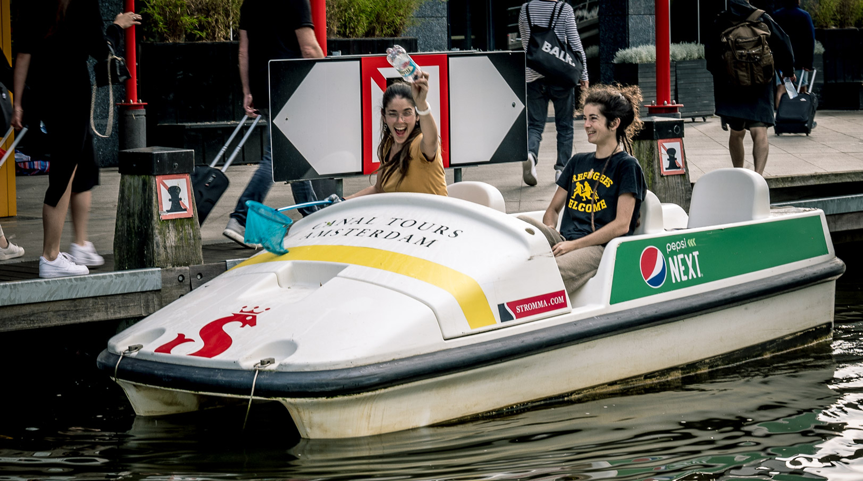 2 mensen in een waterfiets halen afval uit het water